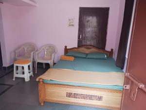 a bedroom with a bed with a wooden headboard and two chairs at GARDEN villa, Vanasthalipuram in Hyderabad