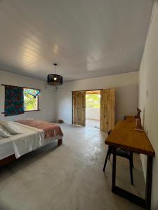 a bedroom with a bed and a wooden table at Casa Cris in Itaúnas