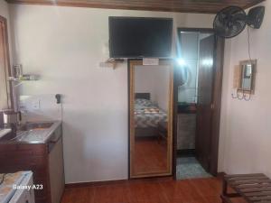 a bathroom with a mirror and a television on a wall at Morada do Sabiá - chalé 1 in Resende