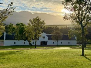 a white building in a field with trees at Webersburg in Stellenbosch