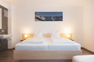 een slaapkamer met 2 witte bedden en een wastafel bij Möslehof in Kauns