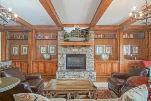 a living room with a stone fireplace and leather furniture at Highland House #102-104: 2Br: 2 Bath in Snowshoe