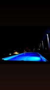 a blue pool at night with a city in the background at B&B Melissa in Noto