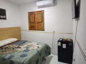 una camera con letto, televisore e finestra di Pousada dos Artistas a Japaratinga