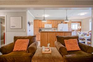a living room with two brown couches and a kitchen at Summit 107B 3Br Condo in Snowshoe +18 photos