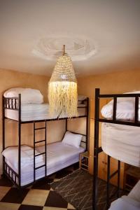 Camera con 4 letti a castello e un lampadario pendente. di Waves House Tamraght - Surf & Chill Hostel a Tamraght Ouzdar