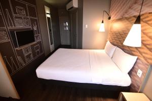 a bedroom with a white bed and two lamps at ibis Natal in Natal