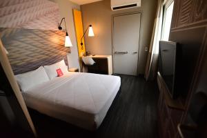 a hotel room with a white bed and a window at ibis Natal in Natal