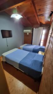 twee bedden in een kleine kamer met een tv bij El Pilo in Centenario