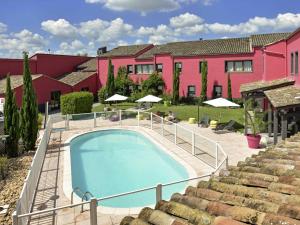 a swimming pool in front of a pink building at ibis Macon Sud Crêches in Crêches-sur-Saône