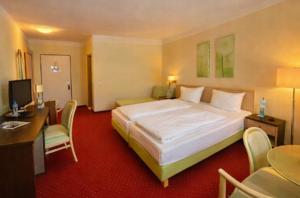 a hotel room with a large bed and a desk at Hotel Phönix in Bad Füssing