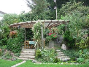 a wooden pergola with a table in a garden at Ferienwohnung Schabmüller in Kelheim