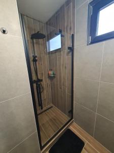 a shower with a glass door in a bathroom at Ohuta-Barn Vendégház in Parád +23 photos