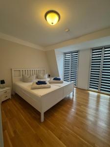 Schlafzimmer mit einem weißen Bett und Holzböden in der Unterkunft Trafford Sky Homes in Leipzig + 18 Fotos