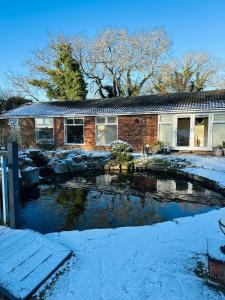 una casa con uno stagno di fronte nella neve di Randall Farm a Fawkham