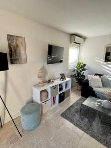 een woonkamer met een bank en een tv bij Résidence Coté Village in Valbonne +14 foto's