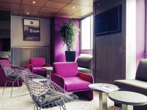 a waiting room with purple chairs and a potted plant at Mercure Epinal Centre in Épinal