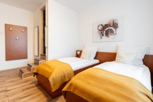 two beds in a room with white walls and wooden floors at Hotel Mutter Buermann Hannover in Hemmingen