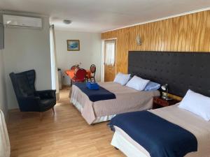een hotelkamer met twee bedden en een stoel bij Hotel Skitniza in Huasco