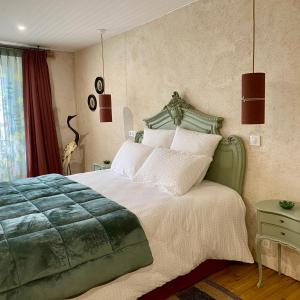 a bedroom with a large green bed with white pillows at Une nuit chez une artisane in Josselin