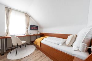 a bedroom with a bed and a desk and a chair at Hotel Mutter Buermann Hannover in Hemmingen