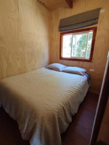 een bed in een kleine kamer met een raam bij Cabaña el Maitén Ensenada in Puerto Varas