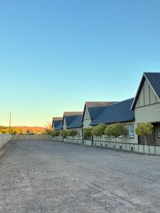 a row of houses with black roofs and a gravel driveway at Gota de Piedra in Añelo