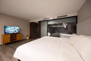 a bedroom with a large white bed and a flat screen tv at Solari 15F Duplex Suite with Nhat Tan Bridge View in Hanoi