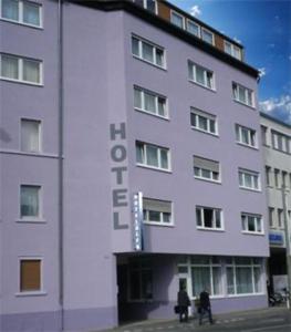two people standing in front of a white building at Alfa Hotel Frankfurt in Frankfurt