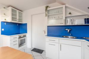 a kitchen with white cabinets and blue accents at Hotel Mutter Buermann Hannover in Hemmingen