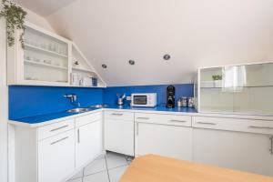 a kitchen with white cabinets and a blue wall at Hotel Mutter Buermann Hannover in Hemmingen +76 photos