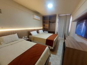 a hotel room with two beds and a flat screen tv at Hotel San Andres in Coronel Oviedo +41 photos
