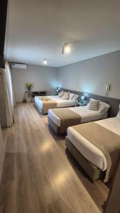 three beds in a room with wooden floors at DAKAR HOTEL in Mendoza