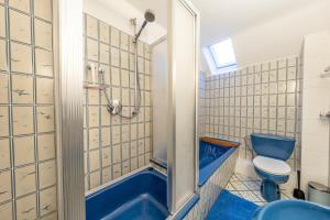 a bathroom with a blue tub and a toilet at Hotel Mutter Buermann Hannover in Hemmingen