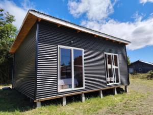 een zwart tiny house met een groot raam bij Cabaña el Maitén Ensenada in Puerto Varas