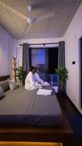 two men sitting on a large bed in a bedroom at Lucky Wave Beach Resort in Colombo