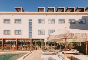 a hotel with a pool and tables and umbrellas at Torel Avantgarde in Porto