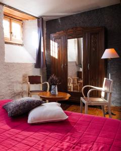 una camera con un letto con una coperta rossa e un tavolo di Auberge l'Escaleta a Seix