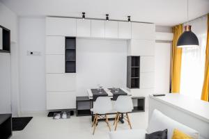 a white kitchen with a table and white chairs at Cazare Voluntari in Voluntari