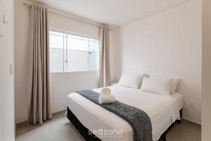 a white bedroom with a large bed with a teddy bear on it at Apartment 100m from Tabuleiro Beachfront CIR0102 in Barra Velha