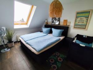 een slaapkamer met een bed met blauwe kussens en een raam bij FeWo - SEEluft am Zwenkauer See in Zwenkau