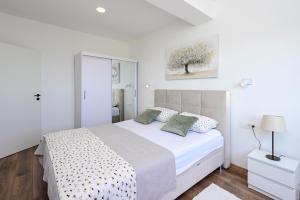 a white bedroom with a white bed with pillows at Apartman Roso in Orebić
