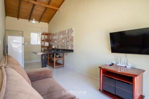 a living room with a couch and a flat screen tv at 2-Bedroom House with Barbecue Area WIL0012 in Imbituba