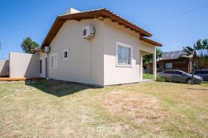 a small white house with a car parked at 2-Bedroom House with Barbecue Area WIL0012 in Imbituba