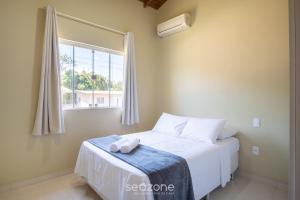 a bedroom with a white bed with a window at 2-Bedroom House with Barbecue Area WIL0012 in Imbituba