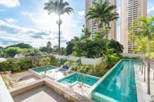 an apartment with a swimming pool and palm trees at Charmosos Flats no Setor Bueno TXP in Goiânia