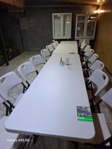 een lange tafel met witte tafels en witte stoelen bij Алрез Гостевой дом in Vardanavan