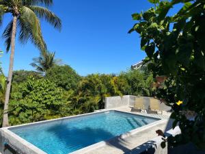 a swimming pool with two chairs and palm trees at O Ti Boneur in Sainte-Rose