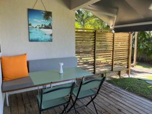 a table and chairs on a deck with a fence at O Ti Boneur in Sainte-Rose