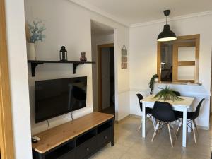 a living room with a television and a table with chairs at Oropesa del Mar Valparaiso Marina Dór in Oropesa del Mar